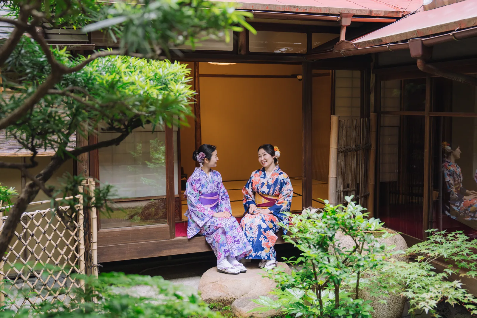 Guests in summer kimono relaxing beside a green Kyoto garden